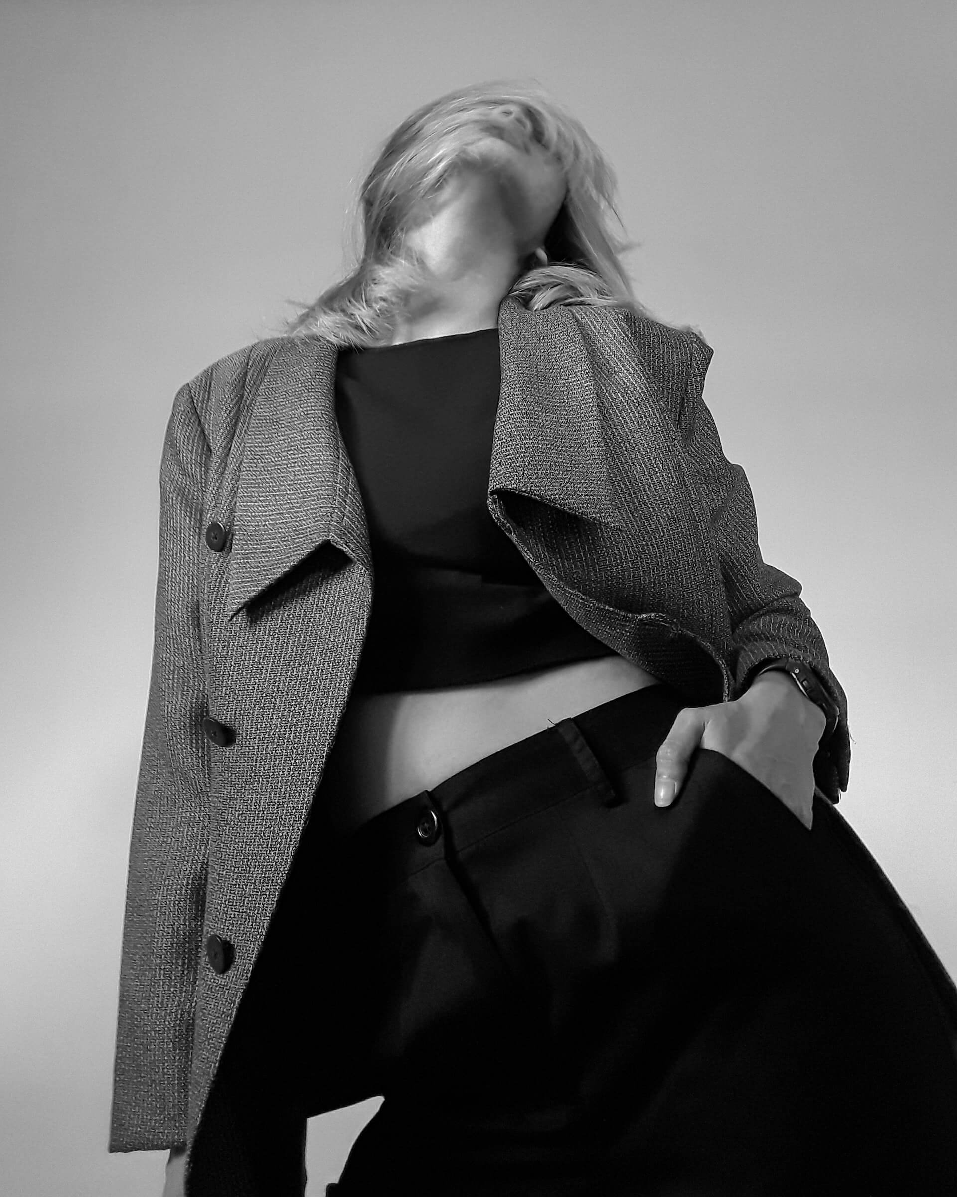 low viewpoint black and white picture of model looking up with hand in pocket.