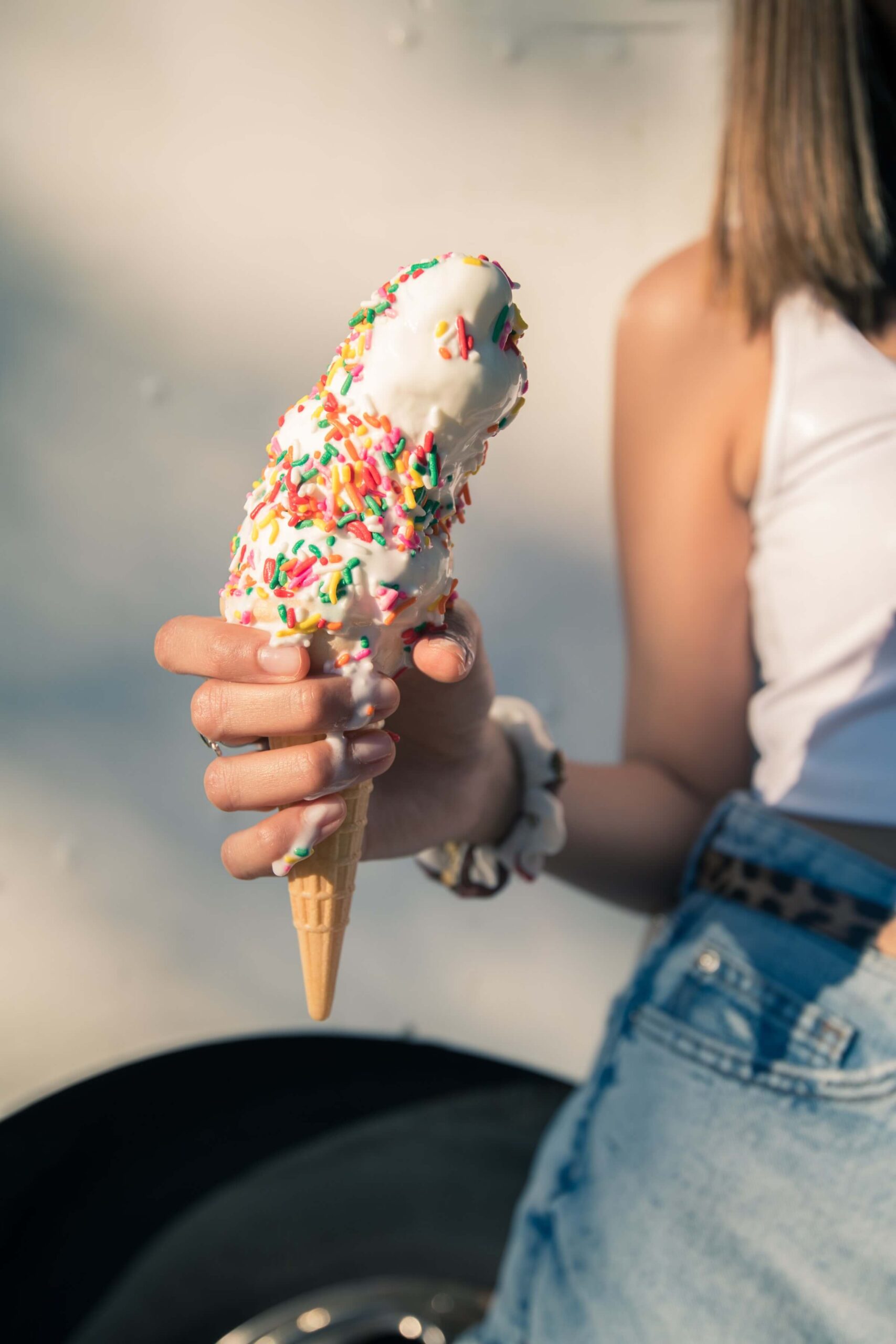 girl holding melting ice cream cone with sprinkles